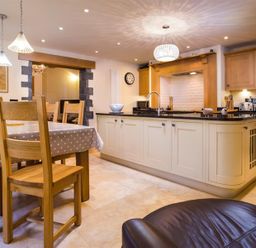 A kitchen with a dining table covered with a polka dot tablecloth and wooden chairs at Oaklea in Ambleside