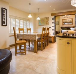 A dining area with a wooden table and six chairs covered by a polka dot tablecloth at Oaklea Ambleside