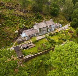 An aerial view of a stone house with a garden and surrounding trees at Oakbank in Langdale