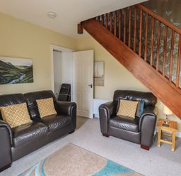 A living room with a sofa and armchair at A River Runs By in Staveley