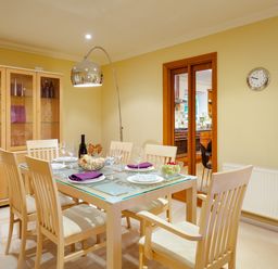 A dining room with a glass table set for six and a wooden cabinet at Merewood Lodge in Ambleside