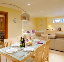 A dining table set with plates glasses and bottles next to a living area with sofas and a television at Merewood Lodge in Ambleside