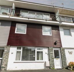 Front view of a multi-story house with brown and white exterior panels and balcony at The Heights in Bowness