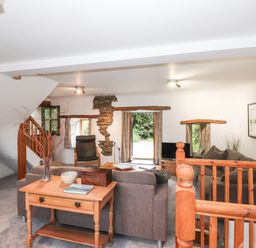 A living room with sofas a wooden table a chair and a television at Cherry Tree Cottage at Satterthwaite in Hawkshead