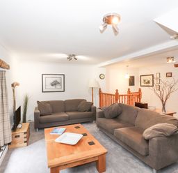 A living room with two brown sofas a wooden coffee table and framed pictures on the wall at Cherry Tree Cottage at Satterthwaite Hawkshead
