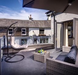 A balcony with a hanging chair sofa and small table at Old Wool Loft in Ambleside