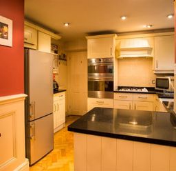 A kitchen with white cabinets black countertops a refrigerator oven stove and microwave at Priory Lodge in Windermere