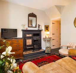 A living room with a fireplace television chest of drawers rug and sofa at The Blithe Hare in Troutbeck Bridge
