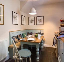 A kitchen dining area with a corner bench seating and table set for a meal at The Blithe Hare in Troutbeck Bridge