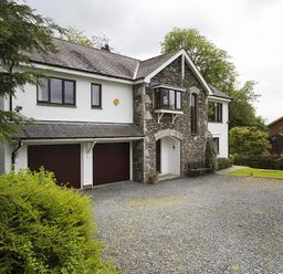 A two-story house with a stone and white exterior and a gravel driveway at March House in Windermere