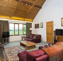 A living room with leather sofas a wooden coffee table a patterned rug and a large window at March House in Windermere