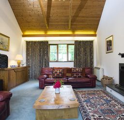 A living room with red leather sofas a wooden coffee table a patterned rug and a fireplace at March House in Windermere