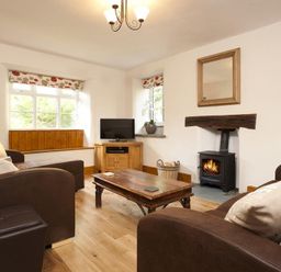 A living room with brown sofas a wooden coffee table a fireplace and a television at Wythebank in Langdale