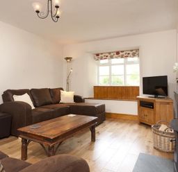 A living room with brown sofas a wooden coffee table a wooden cabinet with a television and a window seat at Wythebank in Langdale