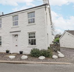 A house with windows and a front door at Smithy Cottage at Bowland Bridge Bowness