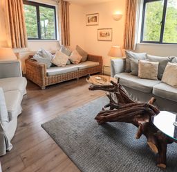 A living room with sofas and armchairs and a wooden coffee table with glass tops at Le Chalet in Elterwater