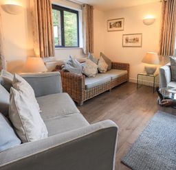 A living room with sofas cushions lamps and framed pictures at Le Chalet in Elterwater