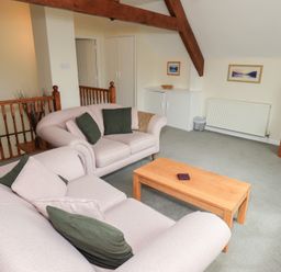 A living room with two sofas green cushions a wooden coffee table a TV on a wooden stand and framed pictures on the wall at The Old Chapel in Crook