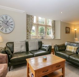 A living room with sofas, a table, and a clock at Middlerigg in Troutbeck