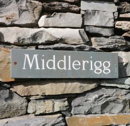 A sign reading 'Middlerigg' on a stone wall at Middlerigg in Troutbeck