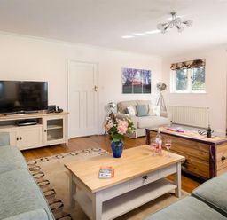 A living room with sofas a television and coffee tables at Juniper Cottage in Windermere