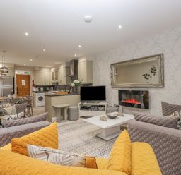 An open plan living room and kitchen with sofas a coffee table a television an electric fireplace and a dining table at Rossett Holme Ambleside