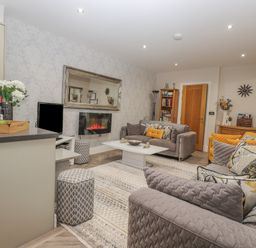 A living room with sofas pillows a coffee table a TV and a fireplace at Rossett Holme in Ambleside