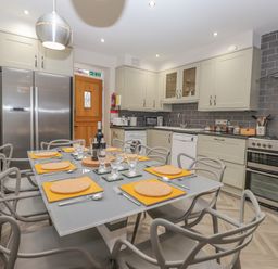 A kitchen with a dining table set for eight people with plates glasses and cutlery at Rossett Holme Ambleside
