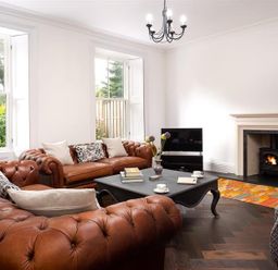 A living room with brown leather sofas a black coffee table a wood stove and a television at Ben House in Grasmere