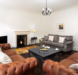 A living room with leather sofas a patterned fabric sofa a fireplace and a coffee table at Ben House in Grasmere