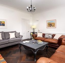 A living room with sofas coffee table lamp and paintings at Ben House in Grasmere