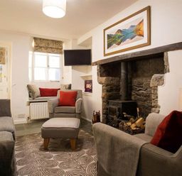 A living room with grey sofas and red cushions a wood burning stove and a wall painting at Lettera in Ambleside
