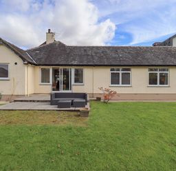 A single story house with multiple windows a patio with outdoor seating and a grassy lawn at Laal Field House in Keswick
