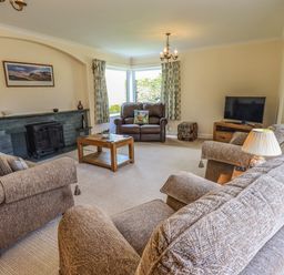 A living room with sofas a coffee table a fireplace and a television at Laal Field House in Keswick