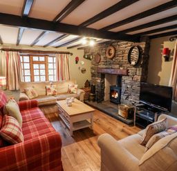 A living room with sofas a stone fireplace and a television at Gunpowder Cottage Langdale