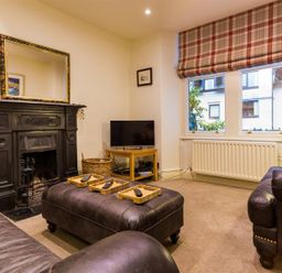 A living room with leather sofas a black fireplace a TV on a wooden stand and plaid window blinds at Orrest Range in Windermere
