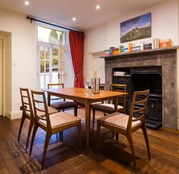 A dining room with a wooden table and six chairs and a fireplace with books on the mantel at Orrest Range in Windermere