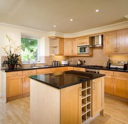 A kitchen with wooden cabinets a black countertop and a kitchen island at The Old Barn in Ambleside