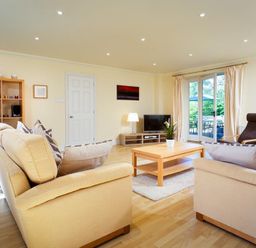 A living room with sofas a coffee table a TV and shelving at The Old Barn in Ambleside