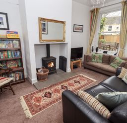 A living room with a wood stove fireplace a bookshelf a television and two sofas at Number Twenty in Keswick