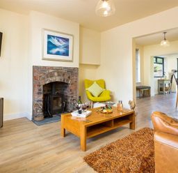 A living room with a brick fireplace a wooden coffee table and modern furniture at Greengarth in Keswick