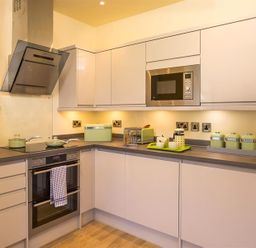 A kitchen with white cabinets a built in microwave an oven stovetop and green kitchen appliances at Greengarth Keswick