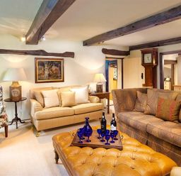 A living room with a beige sofa floral armchair a brown patterned sofa and a tufted ottoman at Fair Rigg Old Farm in Cartmel