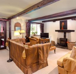 A living room with sofas a wood burning stove and a television at Fair Rigg Old Farm in Cartmel