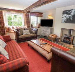 A living room with sofas a wooden coffee table a fireplace and a television at Low Cartmell Fold in Crosthwaite