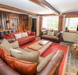 A living room with leather and fabric sofas wooden coffee table red rug and television at Low Cartmell Fold in Crosthwaite