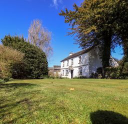 A large lawn with bushes and trees surrounding a white house at Low Cartmell Fold in Crosthwaite