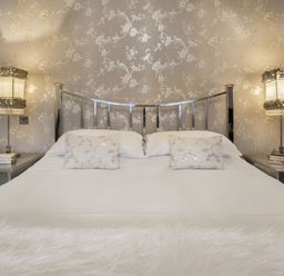A bedroom with a bed with metallic headboard two pillows and bedside tables with lamps at Tent Lodge in Coniston