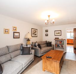 A living room with two grey sofas a wooden coffee table and framed pictures on the wall at Candleberry Cottage in Ambleside