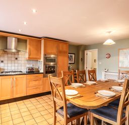 A kitchen with wooden cabinets and a dining table set with plates and cutlery at Candleberry Cottage in Ambleside